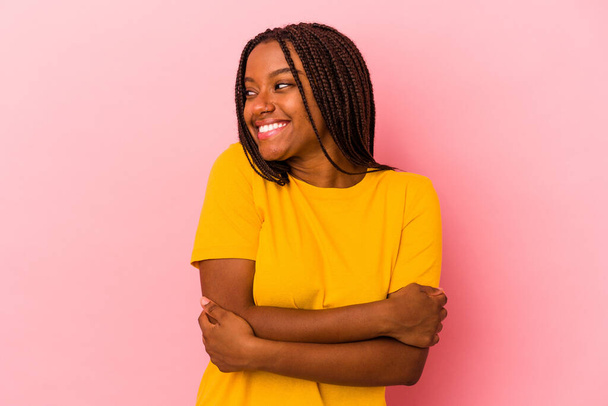 Νεαρή Αφροαμερικανή γυναίκα απομονωμένη σε ροζ φόντο χαμογελώντας με σταυρωμένα τα χέρια. - Φωτογραφία, εικόνα