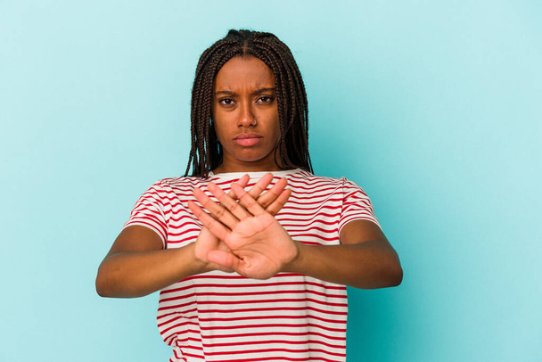 Junge afrikanisch-amerikanische Frau isoliert auf blauem Hintergrund stehend mit ausgestreckter Hand Stoppschild zeigt, verhindert, dass Sie. - Foto, Bild