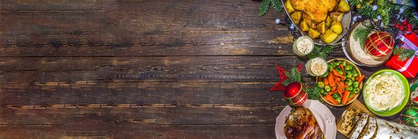 Cena di Natale con cibi tradizionali e prosciutto cotto, pollo, carote arrosto e cavoletti di Bruxelles, patate, con decorazioni natalizie e regali - Foto, immagini