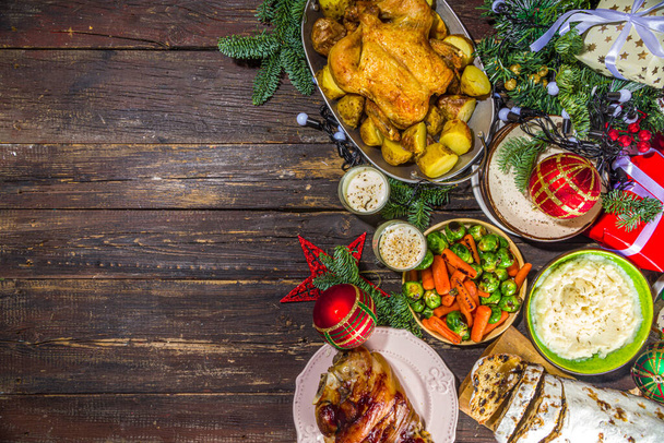 Festive Christmas dinner table with traditional foods and dished  baked ham, chicken, roasted carrots and brussels sprouts, potato, with Christmas decor and gifts - Foto, Bild