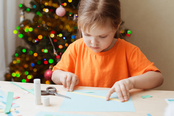 Little Girl Making Christmas Card sitting by table - Foto, imagen