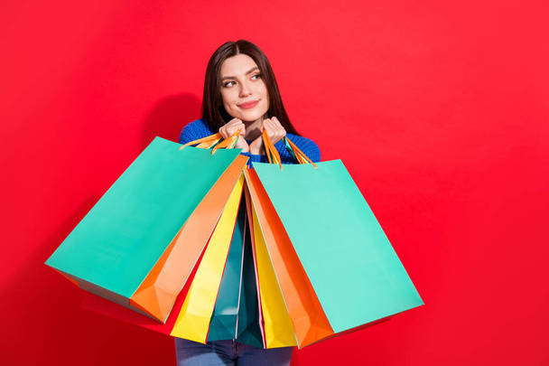 Photo of cheerful young nice attractive woman look empty space hold sale bags isolated on red color background - Fotó, kép
