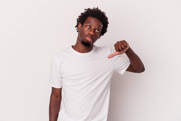 Jovem afro-americano isolado em fundo branco mostrando um gesto de antipatia, polegares para baixo. Conceito de desacordo. - Foto, Imagem