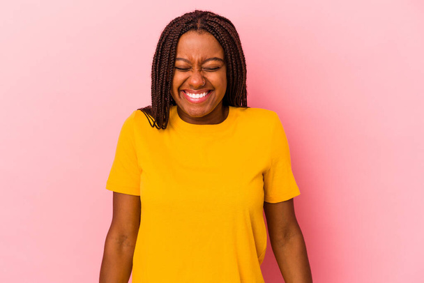 jong Afrikaans amerikaans vrouw geïsoleerd op roze achtergrond lacht en sluit ogen, voelt ontspannen en gelukkig. - Foto, afbeelding
