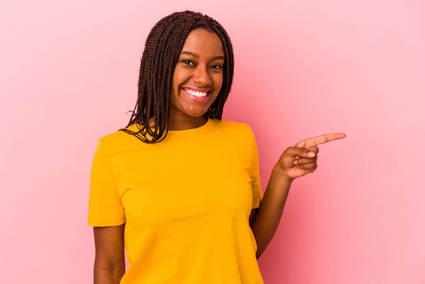 Молодая африканская американка, изолированная на розовом фоне, весело улыбается, указывая указательным пальцем.. - Фото, изображение