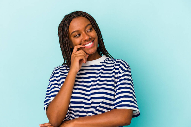 Young african american woman isolated on blue background  relaxed thinking about something looking at a copy space. - Photo, Image