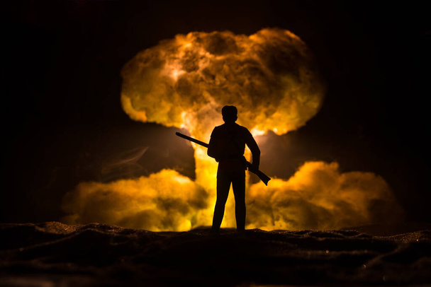 Nuclear war concept. Explosion of nuclear bomb. Creative artwork decoration in dark. Silhouette of soldier standing against giant mushroom cloud of atomic explosion. Selective focus - Photo, image