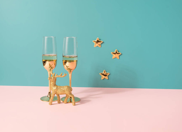 Kieliszki szampana ze złotymi ozdobami na pastelowym tle o dwóch tonach. Tło obchodów Nowego Roku - Zdjęcie, obraz