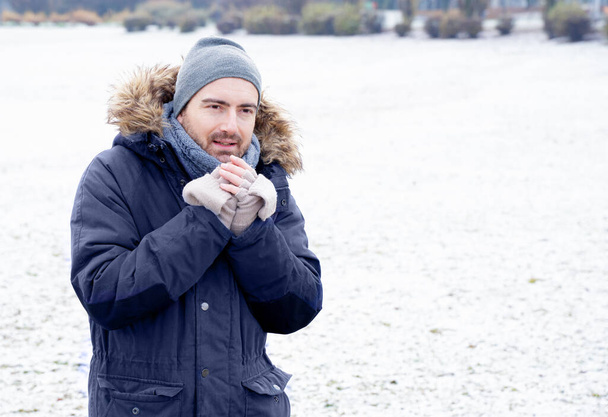 Ένας άντρας ευαίσθητος στο κρύο, παγωμένος στο χιόνι. - Φωτογραφία, εικόνα