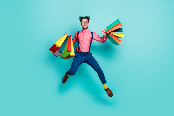 Full length photo of young man happy smile jump up shopper black friday bags isolated over turquoise color background - Foto, imagen