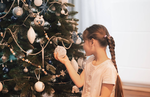 μικρό κορίτσι διακόσμηση χριστουγεννιάτικο δέντρο με τα παιχνίδια στο σπίτι - Φωτογραφία, εικόνα