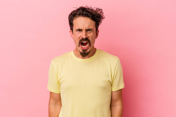 Young caucasian man isolated on pink background shouting very angry, rage concept, frustrated. - Photo, Image