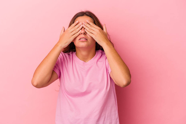 Молодая белая женщина, изолированная на розовом фоне, боится закрывать глаза руками. - Фото, изображение