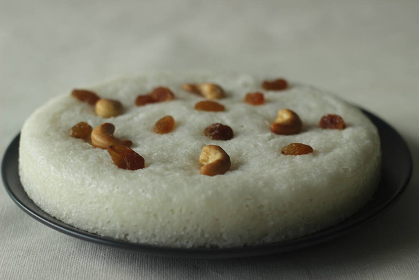 Ваттааппам. Рисовый торт, приготовленный на пару из сладкого бродильного теста риса и кокоса, увенчанный изюмом во время варки. Традиционная закуска из Южного Кералы. Съемка на белом фоне - Фото, изображение