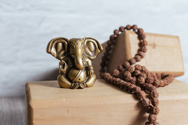 Zbliżenie brązowy posąg hinduskiego boga sukcesu Ganesha. Akcesoria do japońskiej medytacji i drewniane klocki do jogi na drewnianym tle. - Zdjęcie, obraz