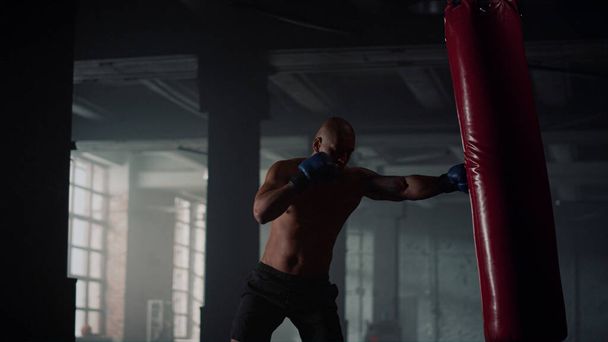 Forte poinçonneuse dans un club de sport. boxeur masculin effectuant l'exercice de force - Photo, image
