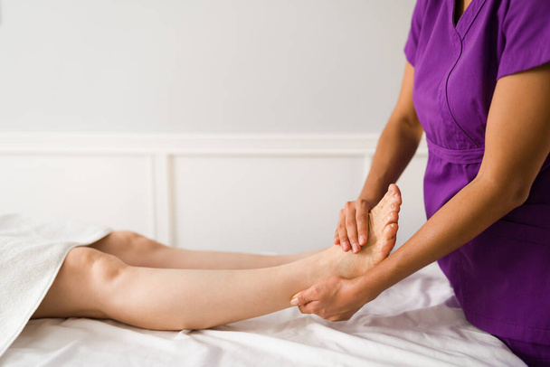Крупним планом іспаномовний масажист дає масаж ноги літній жінці в оздоровчому центрі
 - Фото, зображення