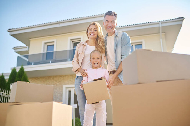Cute family unpacking cardboard boxes while moving to a new house - Foto, imagen