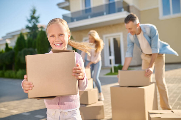 Cute family unpacking cardboard boxes while moving to a new house - Foto, Imagem