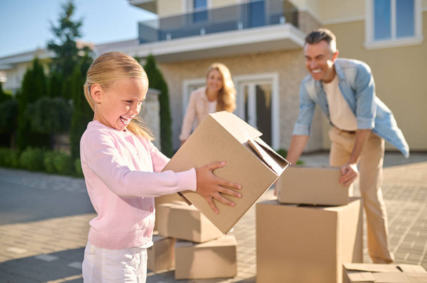 Cute family unpacking cardboard boxes while moving to a new house - Foto, Imagem