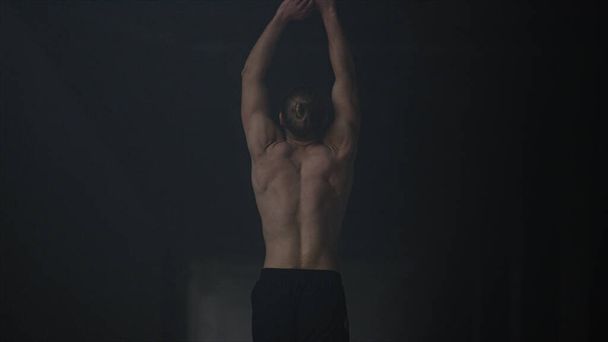 Bodybuilder marche dans un bâtiment sombre. Homme corps chauffant avant l'entraînement d'intensité - Photo, image