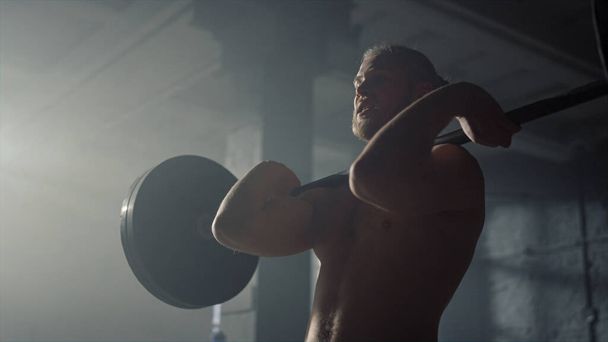 Powerlifter soulevant des poids dans la salle de gym. Homme tenant lourd haltère sur les épaules - Photo, image
