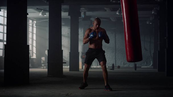 格闘クラブでボクシングの練習をしてる男。パンチングバッグで戦うボクサー - 写真・画像