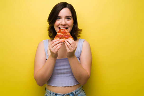 Emocionada joven sintiéndose feliz mientras come deliciosa pizza. Mujer atractiva disfrutando de la pizza - Foto, imagen