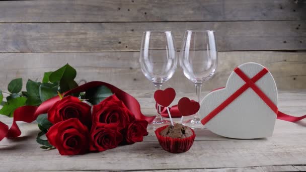 Sevgililer Günü. İki kadeh şampanya, kırmızı güller, tahta arka planda kalp şeklinde bir kutu. Şampanya döküldü..  - Video, Çekim