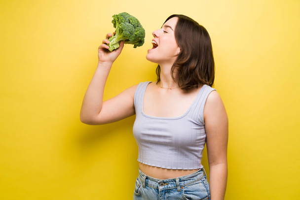 Привлекательная молодая женщина со здоровым образом жизни наслаждается едой брокколи  - Фото, изображение