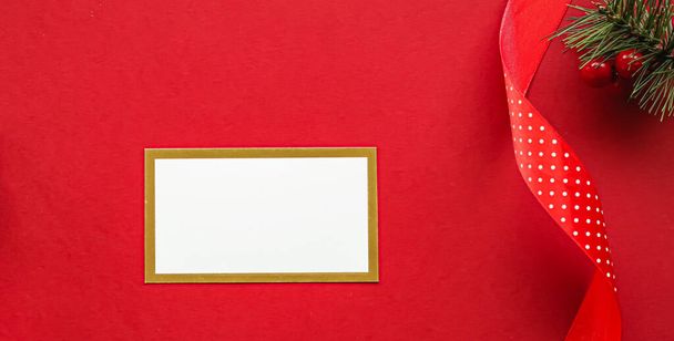 Diseño de identidad de marca de vacaciones y concepto flatlay de Navidad. Tarjeta de visita blanca en blanco y adorno y decoración de Navidad sobre fondo de papel rojo como maqueta plana - Foto, imagen