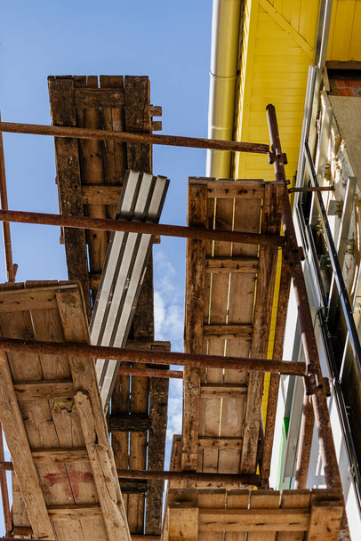 Ponteggi e impalcature con ponti di legno, contro un cielo blu. Esecuzione lavori di costruzione in altezza. Sicurezza delle costruzioni - Foto, immagini