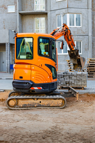 Mini excavator at the construction site. Compact construction equipment for earthworks - Zdjęcie, obraz