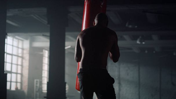 Boxer mlátí sportovní tašku. Silný muž pracuje na foukání na boxovací pytel - Fotografie, Obrázek