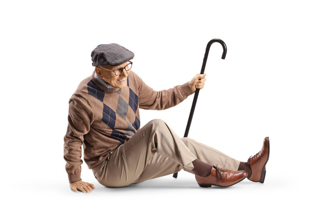Elderly man with a cane sitting on the floor in pain isolated on white background - Foto, Imagen