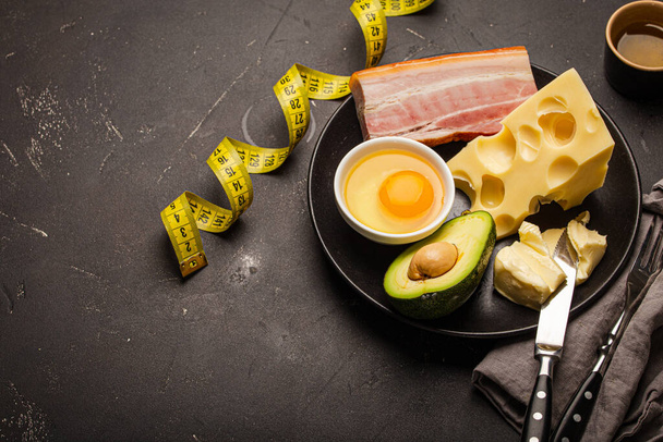 Foods for keto diet on black plate, measure tape on dark background - Photo, Image