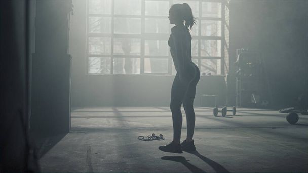 Een vrouw die hurkt tijdens een training in de sportschool. Meisje maken been workout - Foto, afbeelding