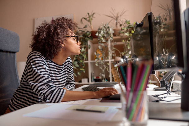 Mujer multiétnica está utilizando la computadora en casa - Foto, Imagen