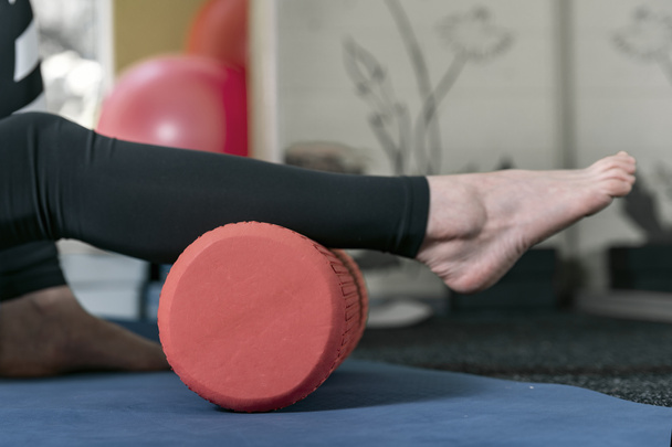 Baldır kaslarını çalıştırmak için paten. Ayak masajı için masaj aleti kullanan bir kadın. Bağ gevşemesi için masaj silindiri - Fotoğraf, Görsel