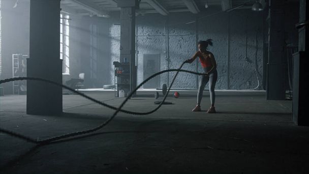 Woman doing workout with battle ropes. Girl performing crossfit exercise  - Photo, Image