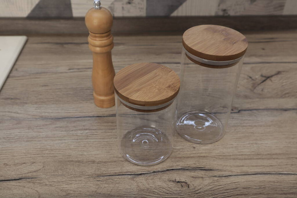 Lege glazen potten met houten deksels voor opslag liggen op tafel. - Foto, afbeelding