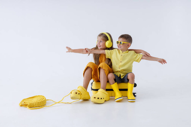 Schattig klein meisje en jongen zittend op reistas - Foto, afbeelding