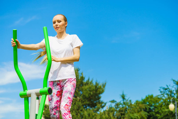 Young woman making exercises on public equipment in city park. Girl working out training in outdoor gym. Healthy lifestyle. - Фото, зображення