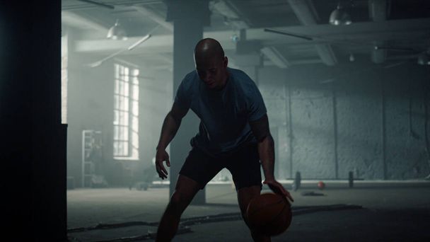 Баскетболист прыгает мячом в спортклубе. Спортсмен дриблинг мяч в тренажерном зале - Фото, изображение