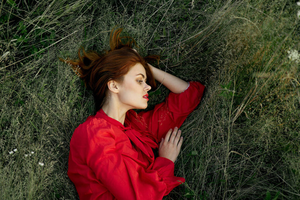 woman in red dress lies on the grass nature freedom summer - Φωτογραφία, εικόνα