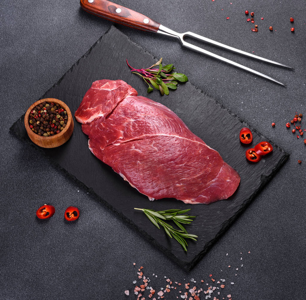 Raw fresh Chuck roll steak with herbs and salt on a cutting Board. Gray background - Foto, imagen