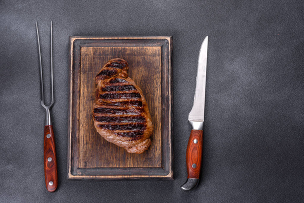 Cooked grilled Chuck eye roll steak on a chopping Board. Dark background - Fotó, kép