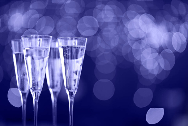 Copos de champanhe no fundo luzes. Fundo de celebração. Cor de 2022 ano, muito peri, violeta - Foto, Imagem