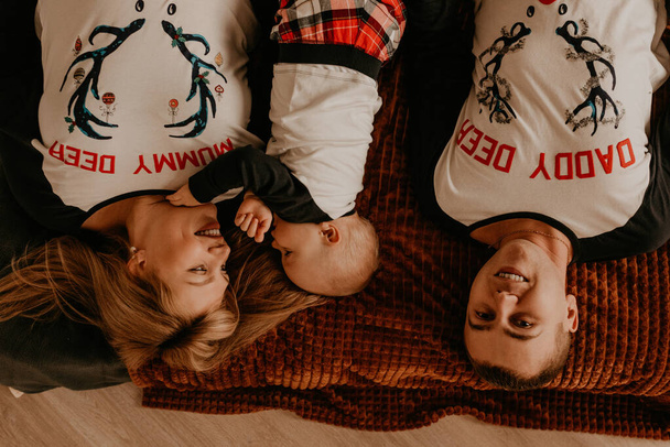 alegre familia feliz en pijama con un niño se acuesta en la cama en el dormitorio. ropa de la familia del año nuevo se ve trajes. Regalos de celebración del día de San Valentín - Foto, Imagen