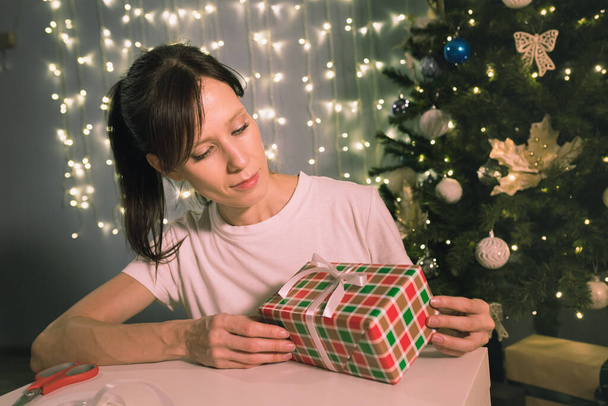 Wrapping Christmas gift. Woman decorating stylish gift in craft paper in home - Photo, image